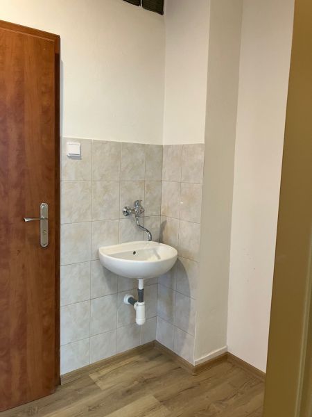 A small sink with tiles and a wooden decor floor in the office.