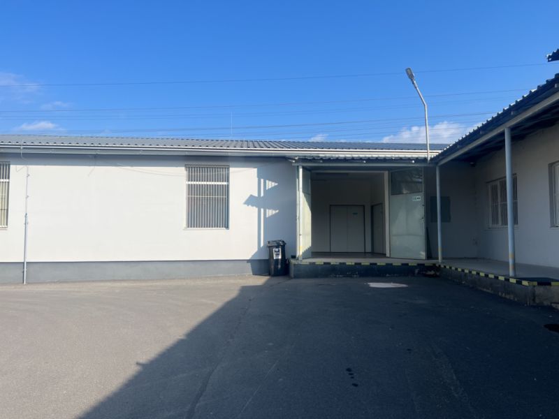 In the area of warehouses and halls in the Banská Bystrica district, in front of a white building with doors.