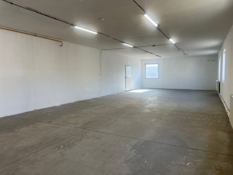 A spacious empty interior with a concrete floor and white walls in warehouses and halls.