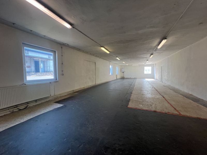 The interior photograph depicts an empty space with a black floor and windows, warehouses and halls.