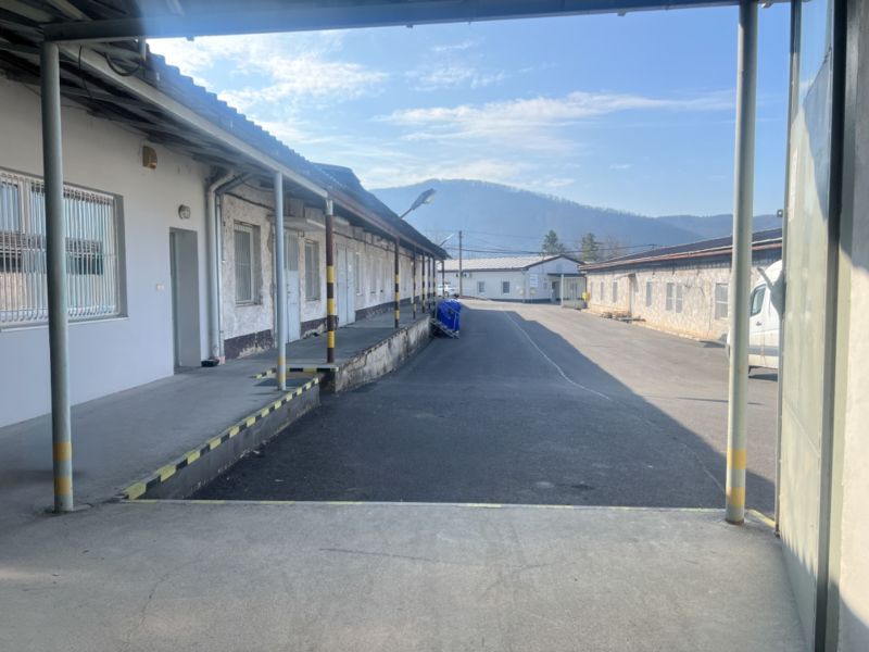 Industrial buildings and warehouses on Cementárenská Road, in Senica, surrounded by mountains.