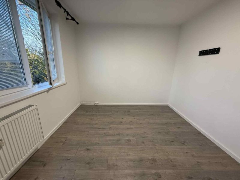 A bright room with a wood-decor floor and a radiator in a 4-room apartment.