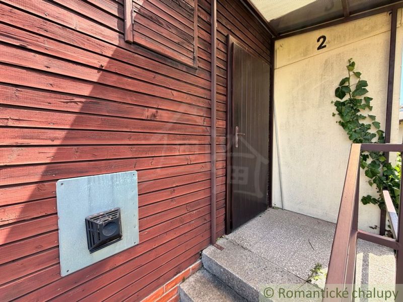 Entrance to the wooden cabin in Nové Zámky with climbing plants on the wall.