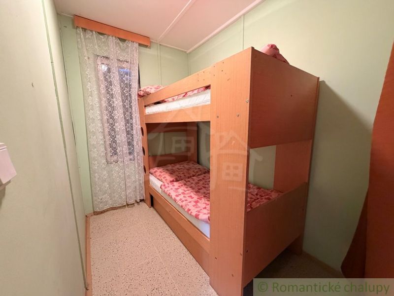 Bunk bed in a cabin room with a curtain with a floral pattern.