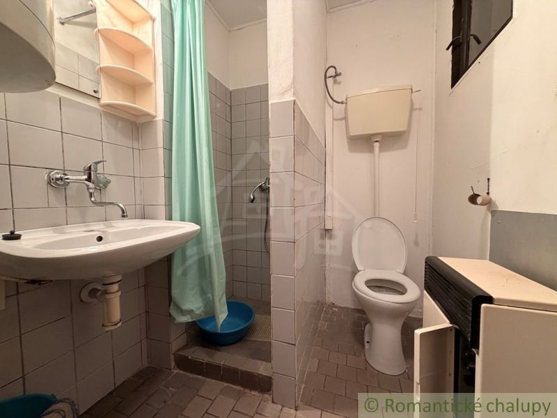 A bathroom in a cottage with a toilet, sink, and shower with a turquoise curtain.