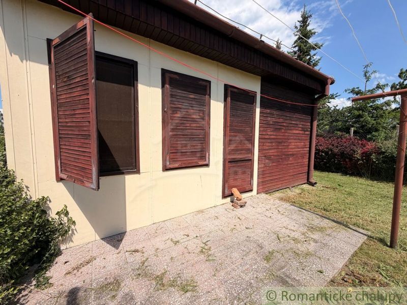 A cottage in Nové Zámky with wooden shutters and a landscaped garden.