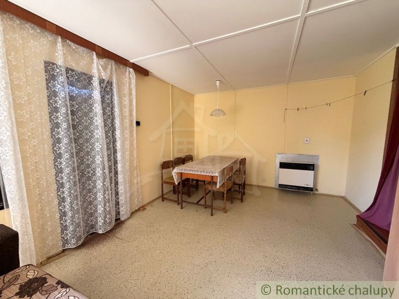 A dining room in a cottage with a wooden decor floor and curtains.