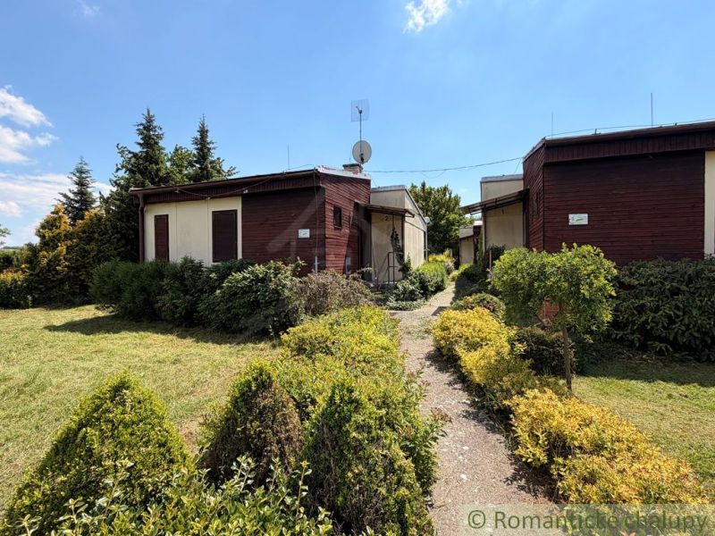 Garden cottages surrounded by greenery in the town of Nové Zámky under a blue sky.