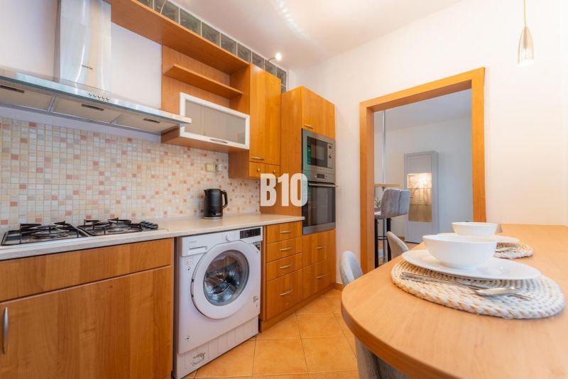 A kitchen with a gas stove, dishwasher, and bar table in a 2-room apartment.