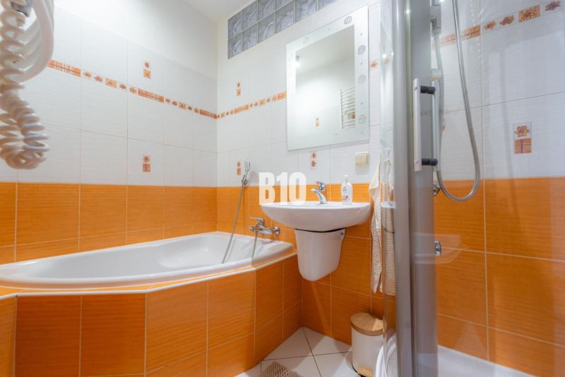 A bathroom in a two-room apartment with dominant orange tiles and a bathtub.