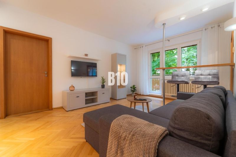 Living room in a 2-room apartment with a wooden decor floor and window seating.