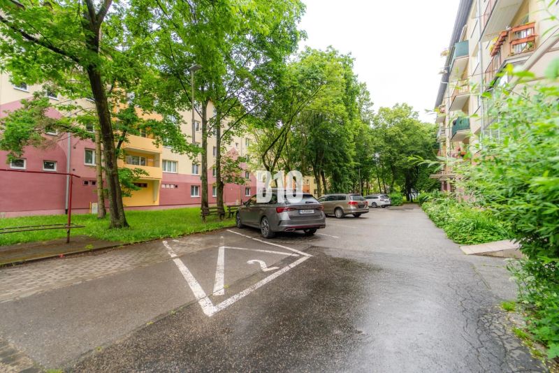 A parking lot with cars and residential buildings surrounded by greenery in Martin.