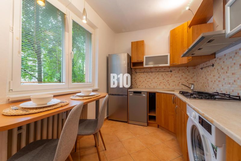 A kitchen in a 2-room apartment with a wooden decor and appliances, beautifully illuminated.