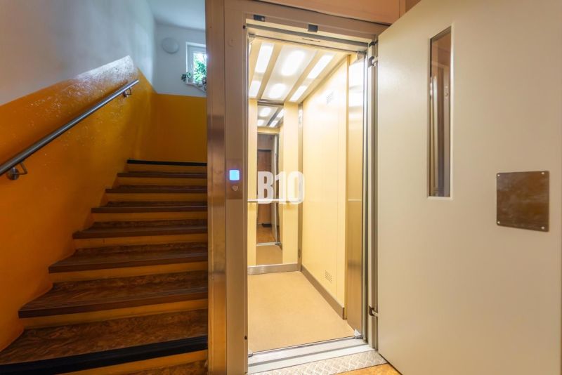 A staircase of a building with an open elevator and yellow walls in an apartment building.