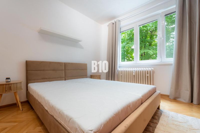 A bedroom in a 2-room apartment with a large window and a floor with a wood decor.
