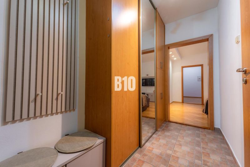 Entrance hallway with a coat rack, mirrored wardrobe, and wooden decor flooring in a 2-room apartment.