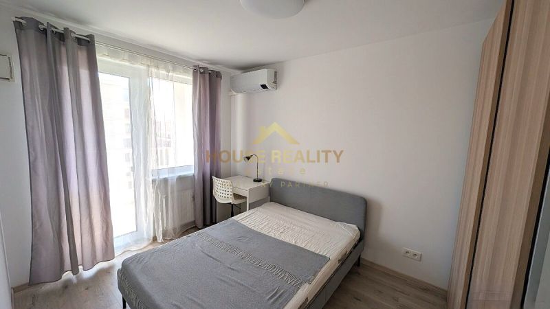 A stylish bedroom with a bed, a table, and a wooden decor floor in a two-room apartment.