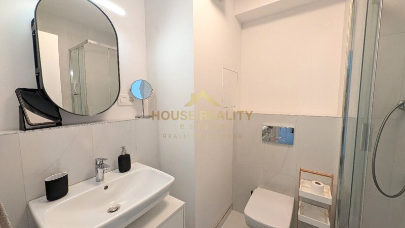 Bathroom with a sink, mirror, and shower in a 2-room apartment.