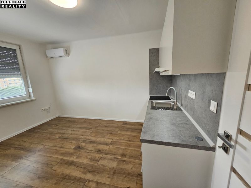 Studio apartment with a kitchenette and wooden decor flooring, air conditioning, and a window.