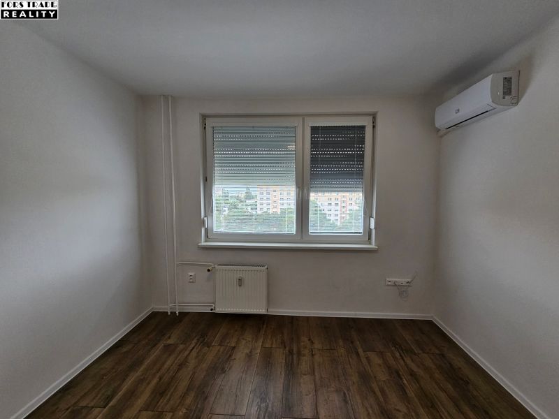 A studio apartment with wood-patterned flooring, air conditioning, and a radiator.