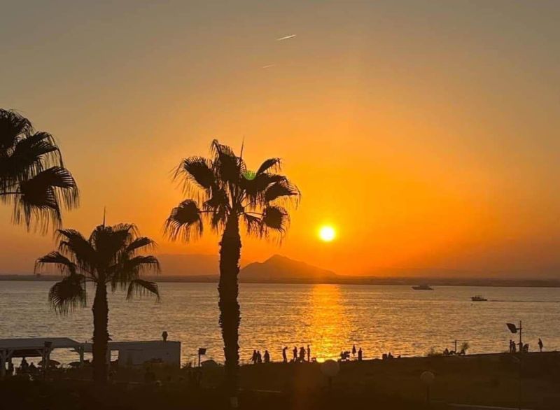 Sunset with palm trees and the sea in La Manga del Mar Menor, Spain.