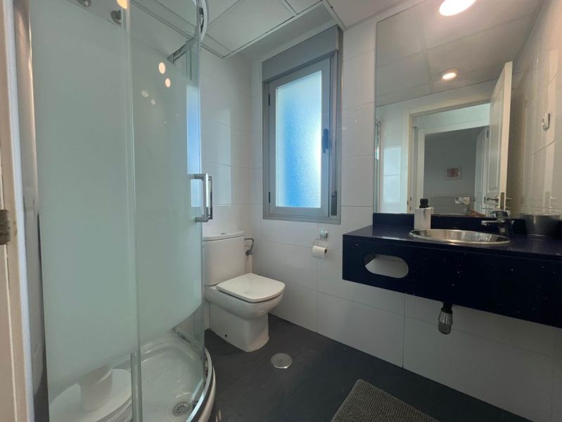 Bathroom with toilet, shower, and sink in a holiday apartment.
