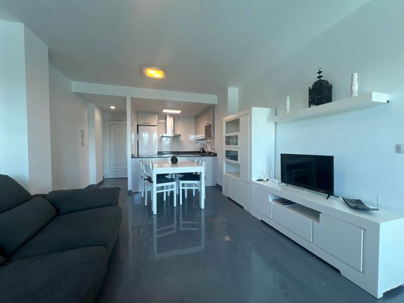 Recreational apartment with a sofa, dining table, and TV, floor with wooden decor.