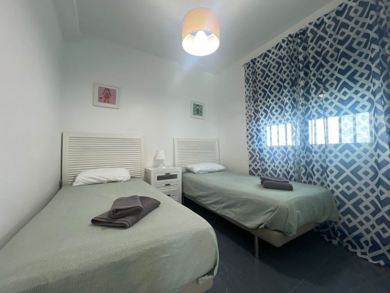 Recreational apartment with two single beds, patterned curtains, and a table with a lamp.
