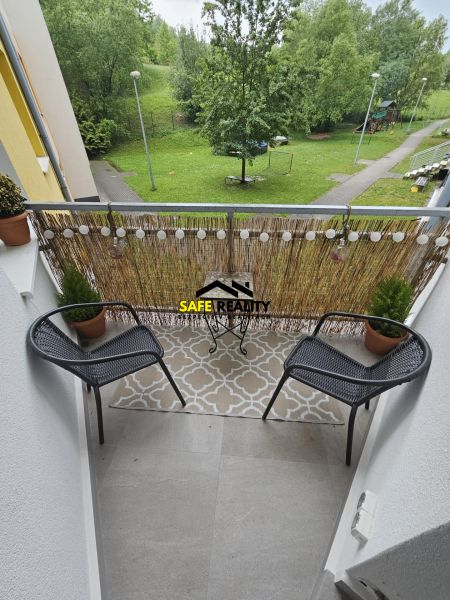 The balcony of the 3-room apartment offers a view of greenery and a children's playground.