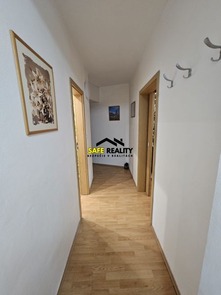 A hallway with light walls and a wooden decor floor in a 3-room apartment.