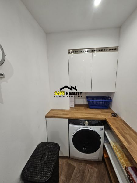 Laundry room in a 3-bedroom apartment with a washing machine, storage spaces, and a floor with a wood decor.