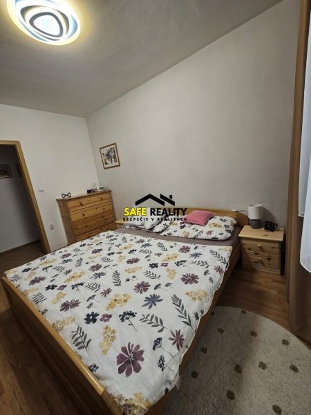 A bedroom in a 3-room apartment with a bed, a dresser, and a floor with a wooden decor.