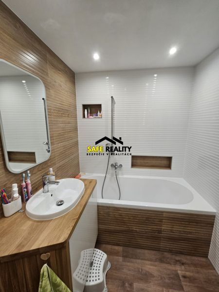 A bathroom in a 3-room apartment with a bathtub and wood decor.