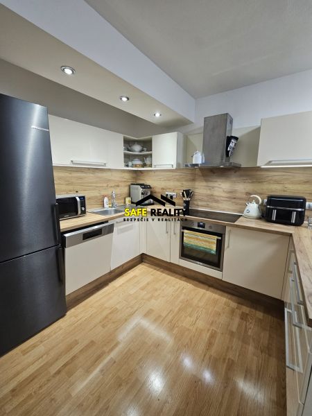 A kitchen in a 3-room apartment with a wood-patterned floor and modern appliances.