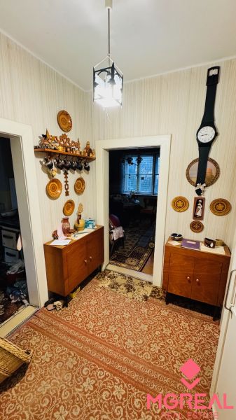 A hallway in a 3-room apartment with furniture, a carpet, and wooden decor on the walls.