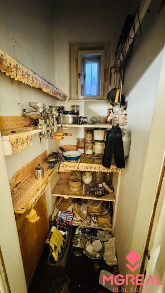 A pantry with shelves in a 3-room apartment, full of kitchen utensils and canning jars.