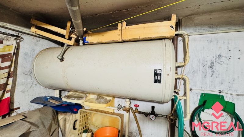 Boiler in the technical room of a 3-room apartment, pipes, hoses, walls.