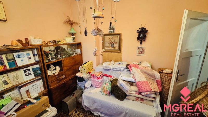 A room in a 3-room apartment with a bed, blankets, and a bookshelf with books.
