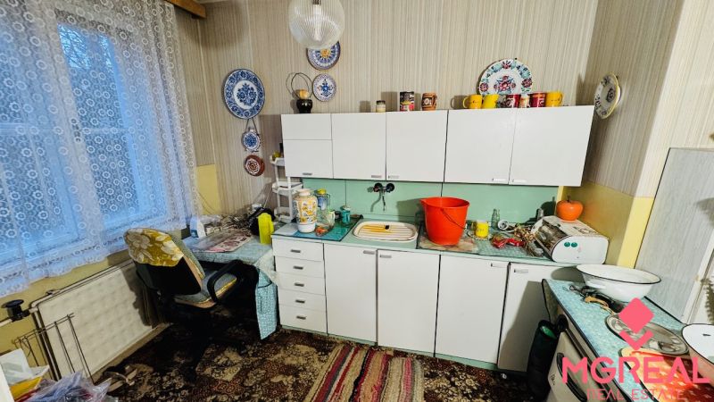 A kitchen in a 3-room apartment with curtains, lace decorations, and antique furniture.
