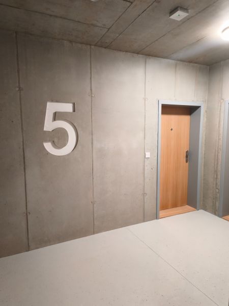 Concrete wall with the number five and wooden doors in a two-room apartment.
