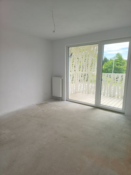 A room in a 2-room apartment with a balcony, a large window, and a radiator on the wall.