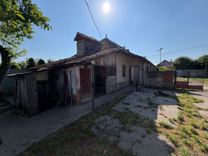 A family house in Nesvady with a damaged roof and a sunny yard.