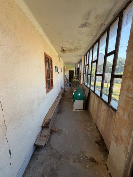 A narrow hallway with a veranda in a family house with old windows and cracked walls.