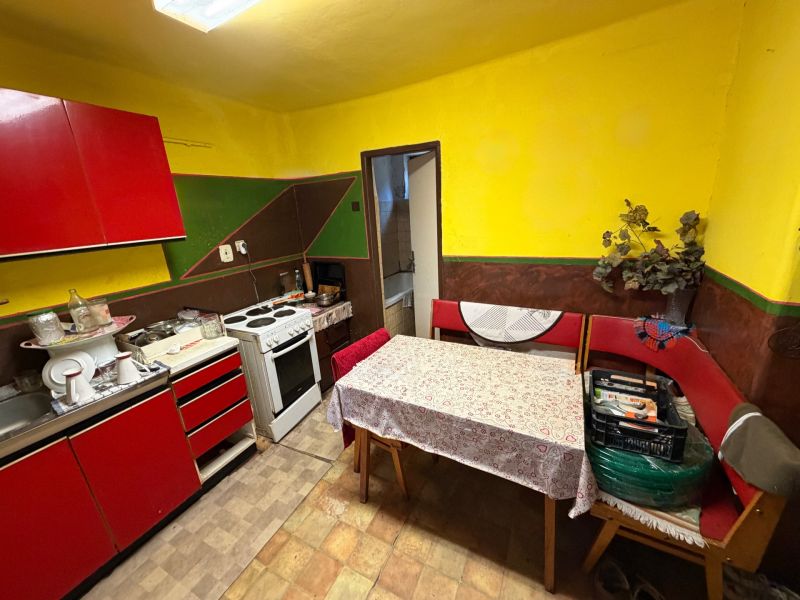 A kitchen in a family house with red furniture, a table, and an electric stove.
