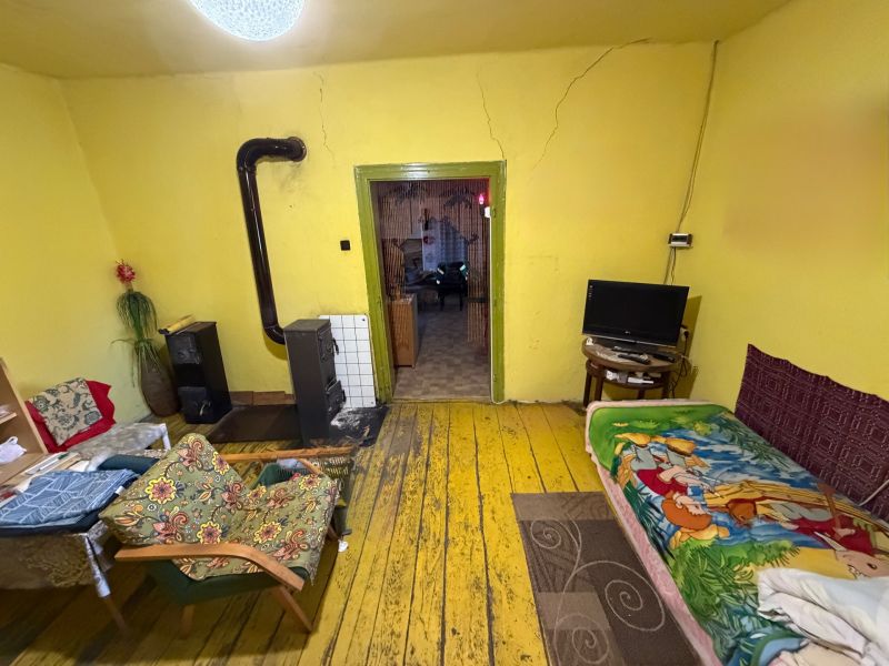 A room in a family house with a stove, yellow walls, and a floor with a wooden decor.