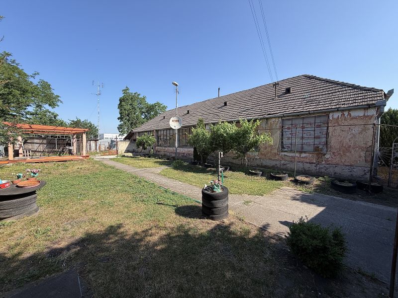 A family house in Nesvady with an unmaintained facade, a wooden pergola, and a landscaped garden.