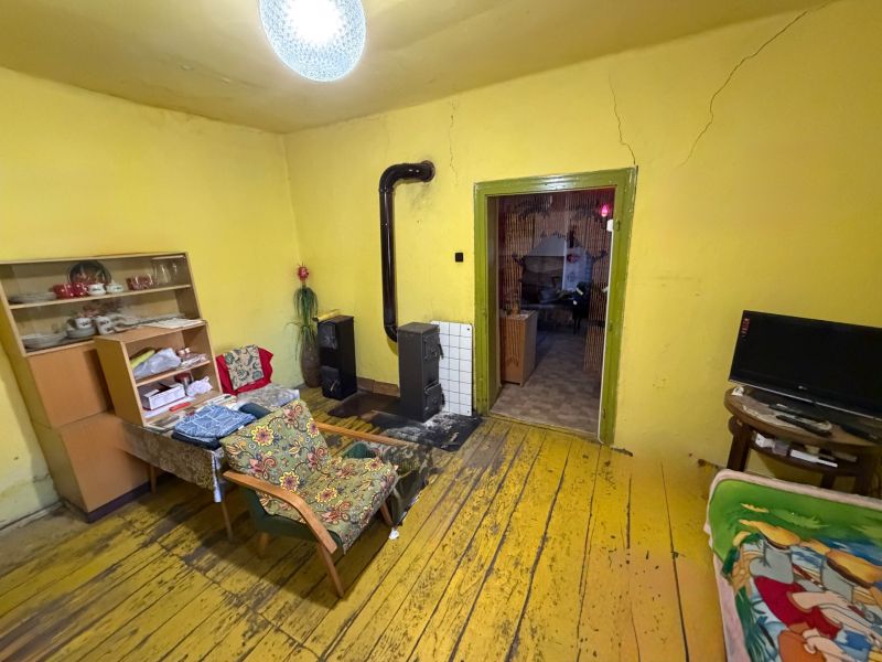 Living room in a family house with a stove, yellow walls, and a floor with a wood decor.