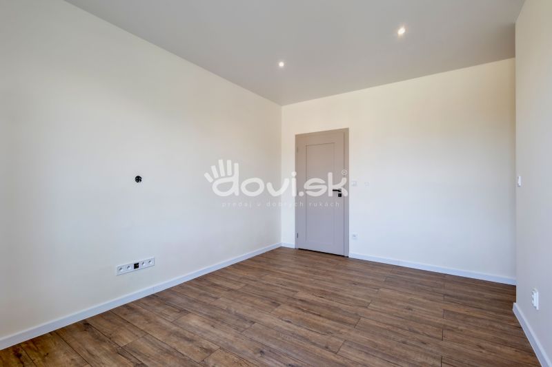 An empty room with a wooden decor floor and light walls in a family house.