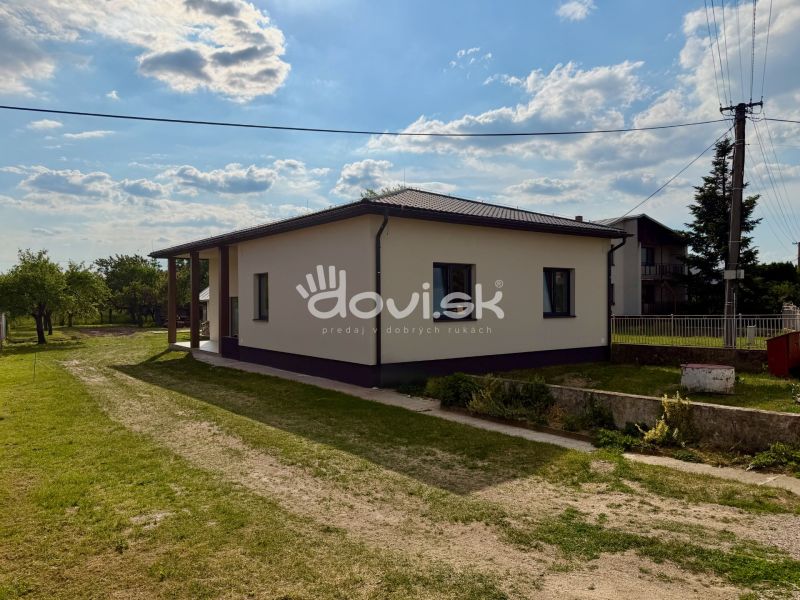 A family house in Zemplínska Široká surrounded by greenery, with a clear sky above the roof.