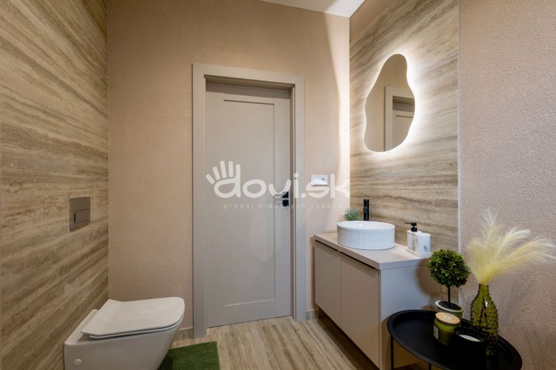 Bathroom in a family house with a sink and LED mirror, with decorative plants.